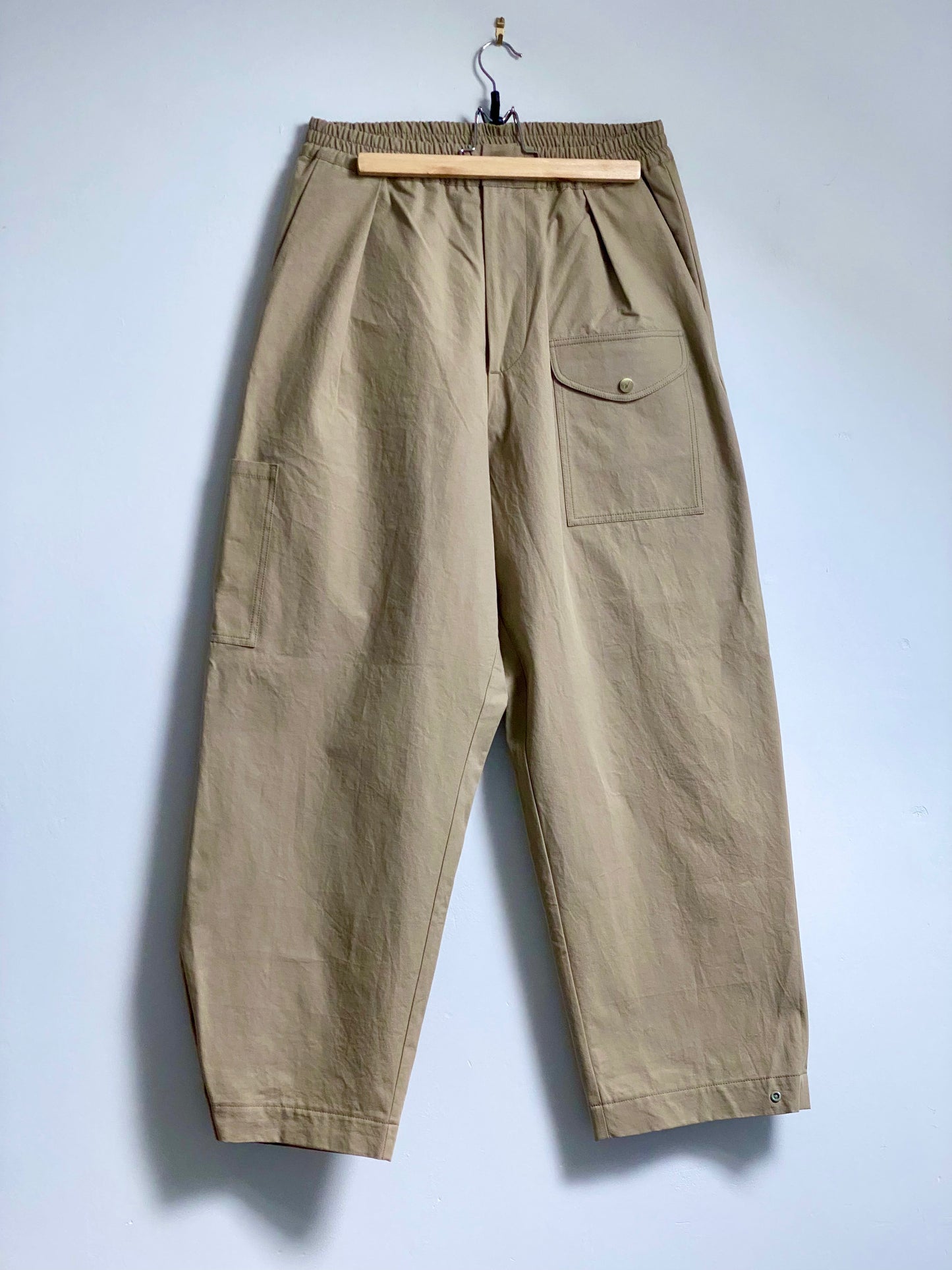 Fawn trousers with a front thigh pocket against a white background