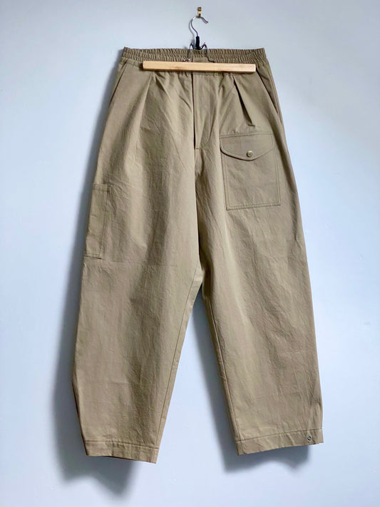 Fawn trousers with a front thigh pocket against a white background