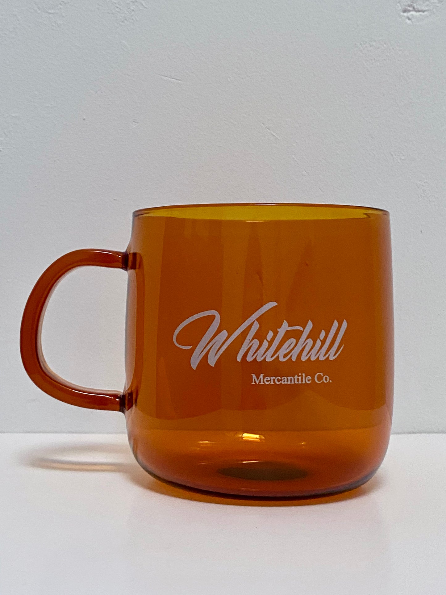 Amber glass cup with Whitehill branding in white